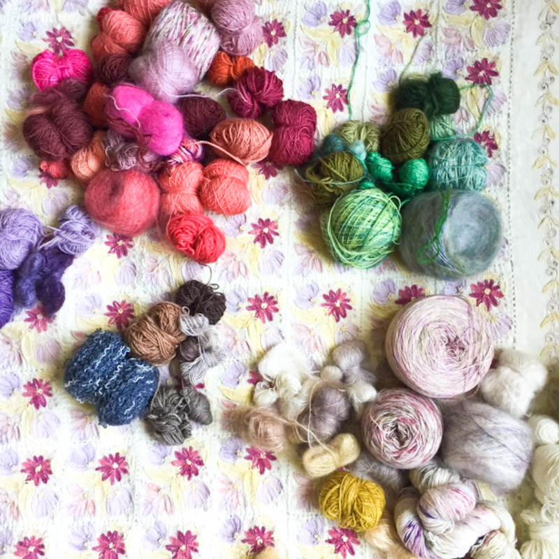 Collection of Cowgirlblues yarns in different colours on a patterned background