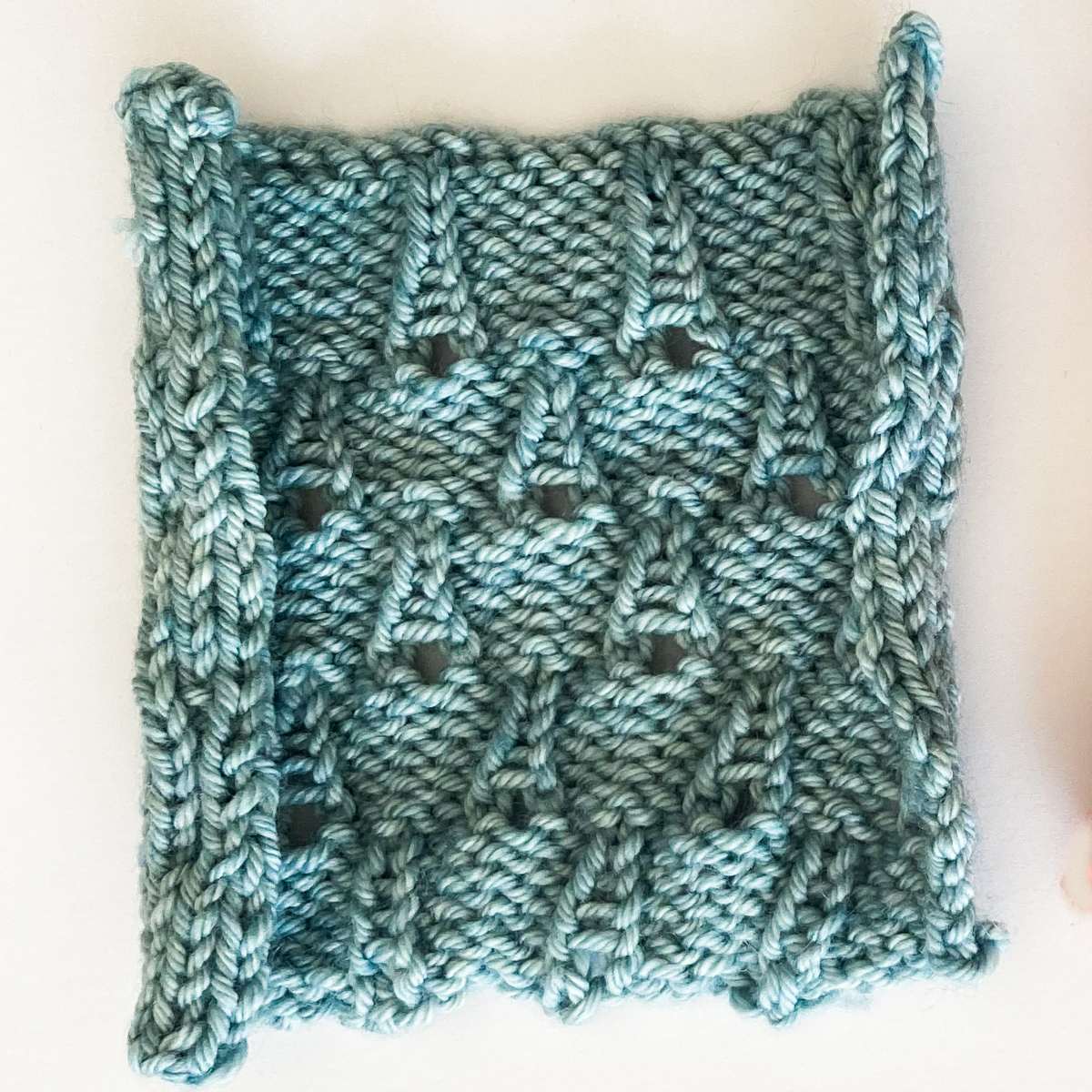Raindrop stitch swatch laying flat knit in Cowgirlblues Merino DK colour Seagrass.