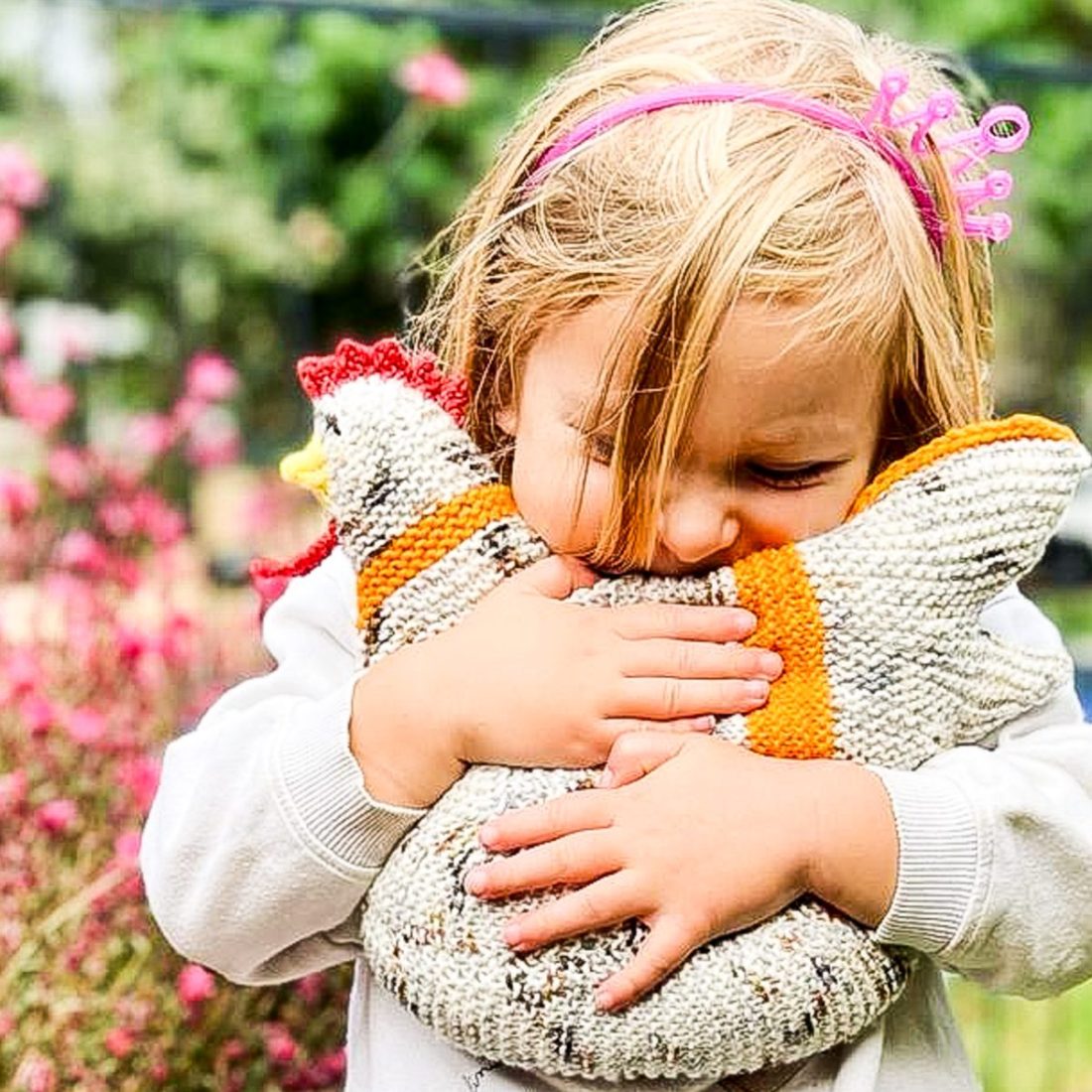 A young child squeezing a knitted chicken